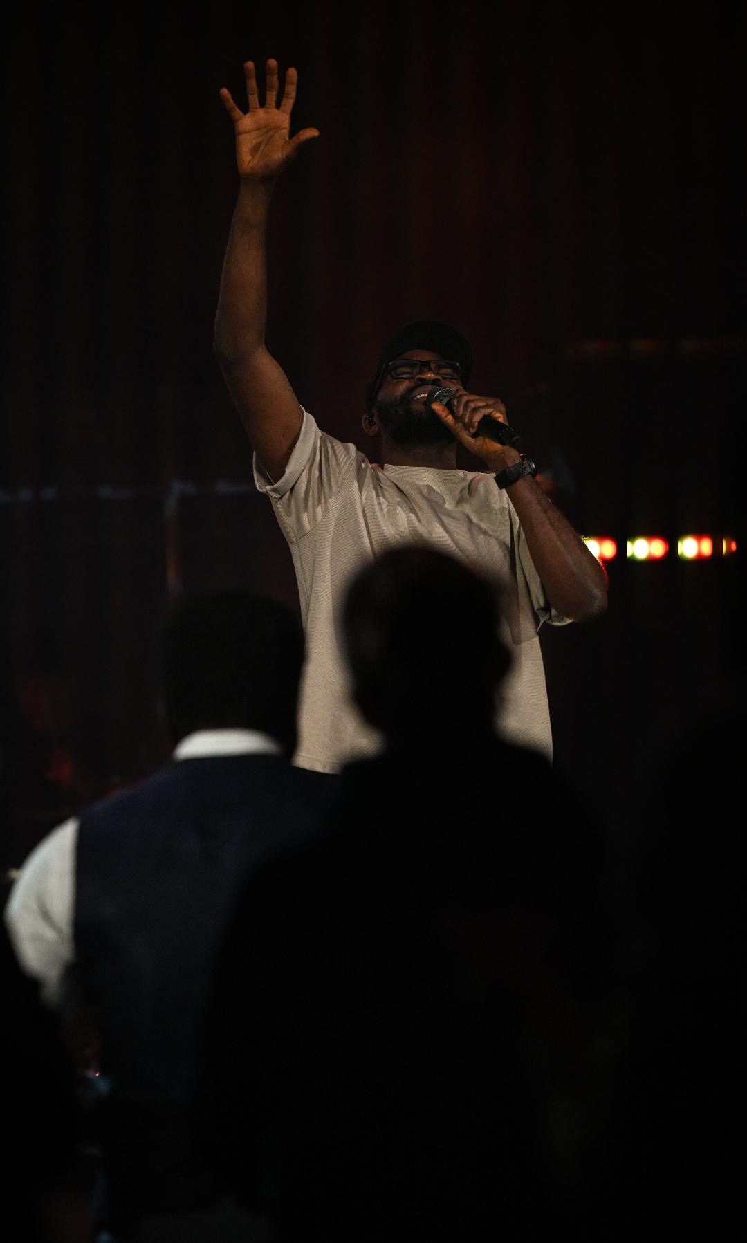 Manuel Sogein leading worship with his hand raised