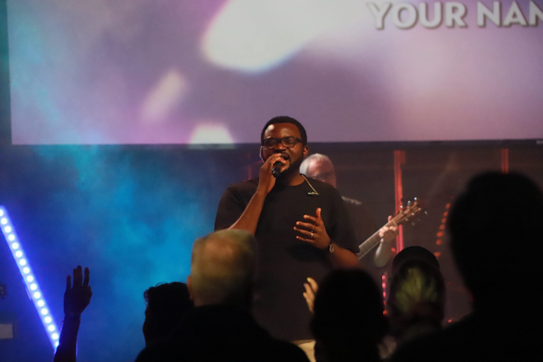 Manuel Sogein leading worship on stage with a band